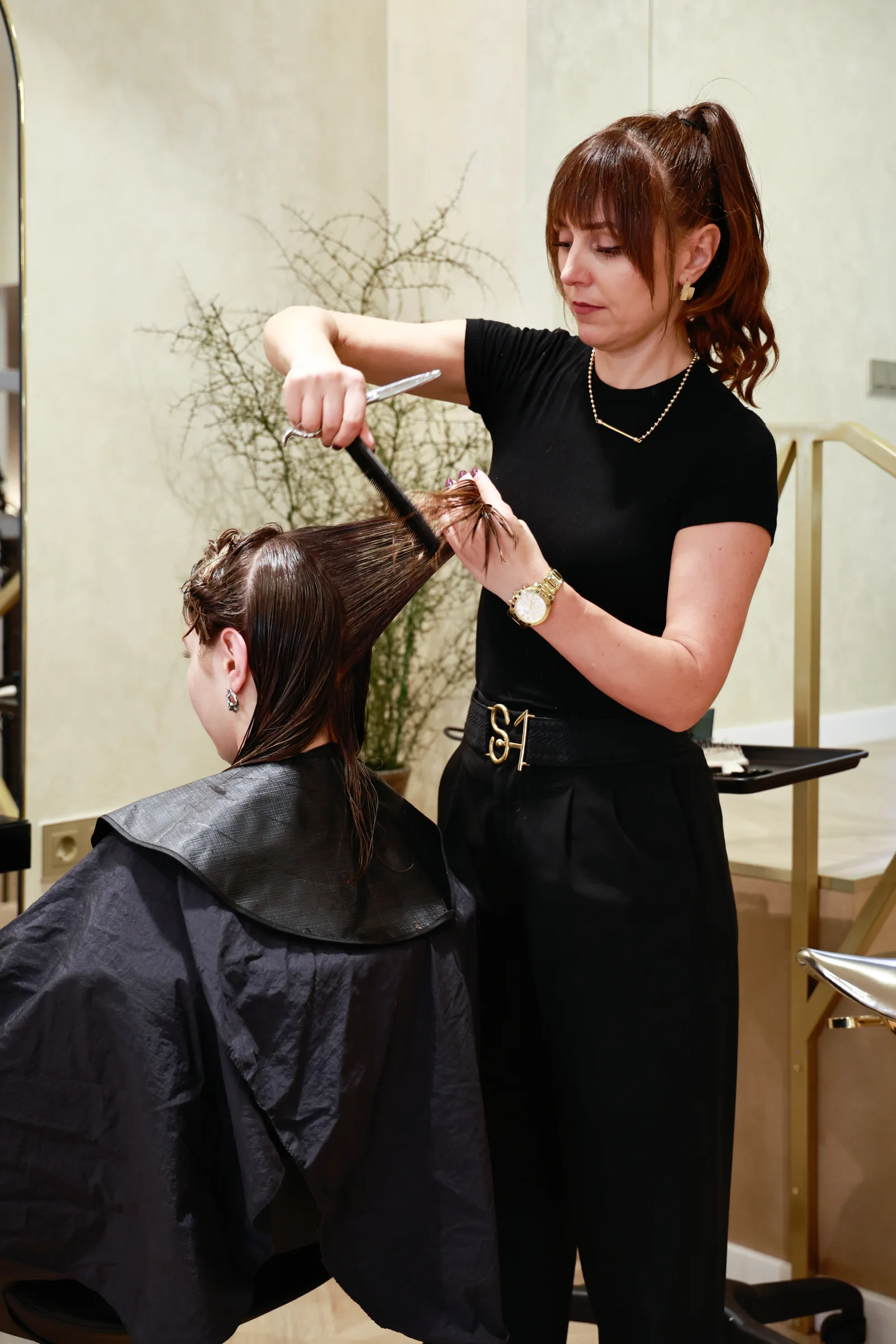 Profesional de Salón Anzhela cortando el cabello de una clienta.